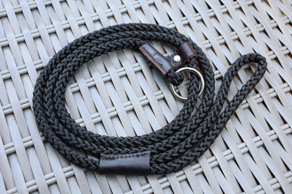 A close up on the black thin nickel slip lead showing the tight braid and the leather stopper and binding around the handle and ring loop.