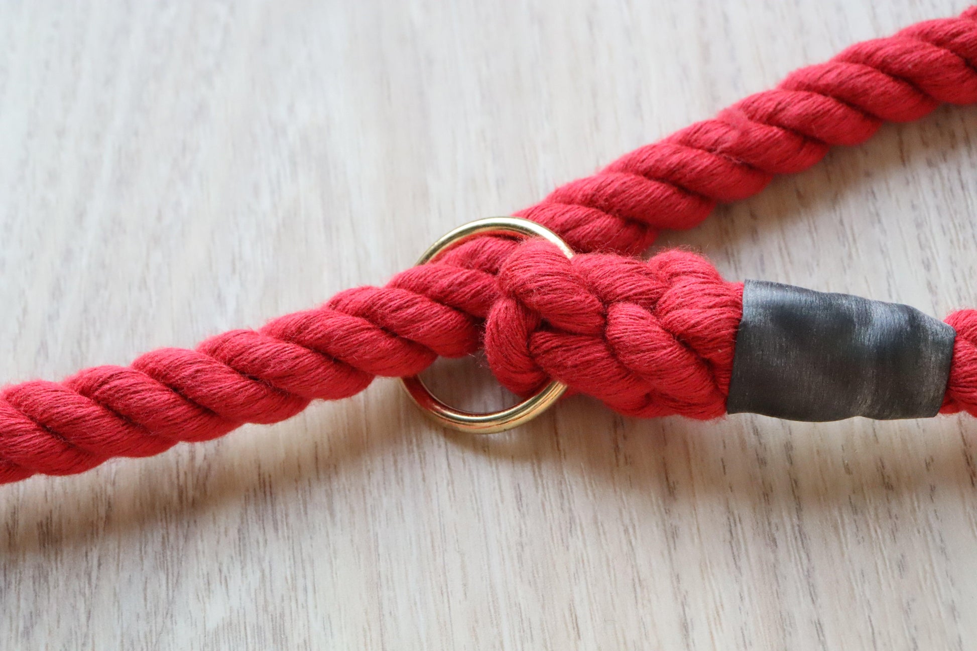 A close up on the cotton texture of this raspberry cotton  slip lead with the brass plated ring  and a rubber wrap to cover the hand splicing that joins the end of the rope back together.